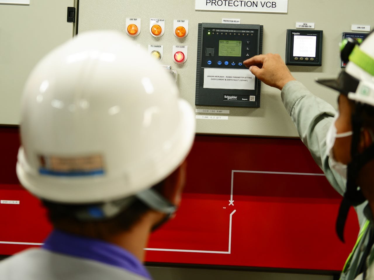 Engineers wearing safety gear operate a control panel in an Indonesian facility.